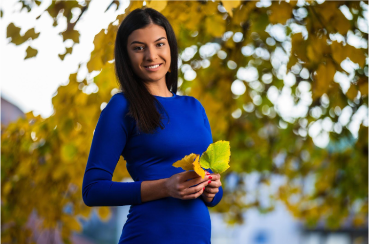 A young woman outside wearing a royal blue dress.